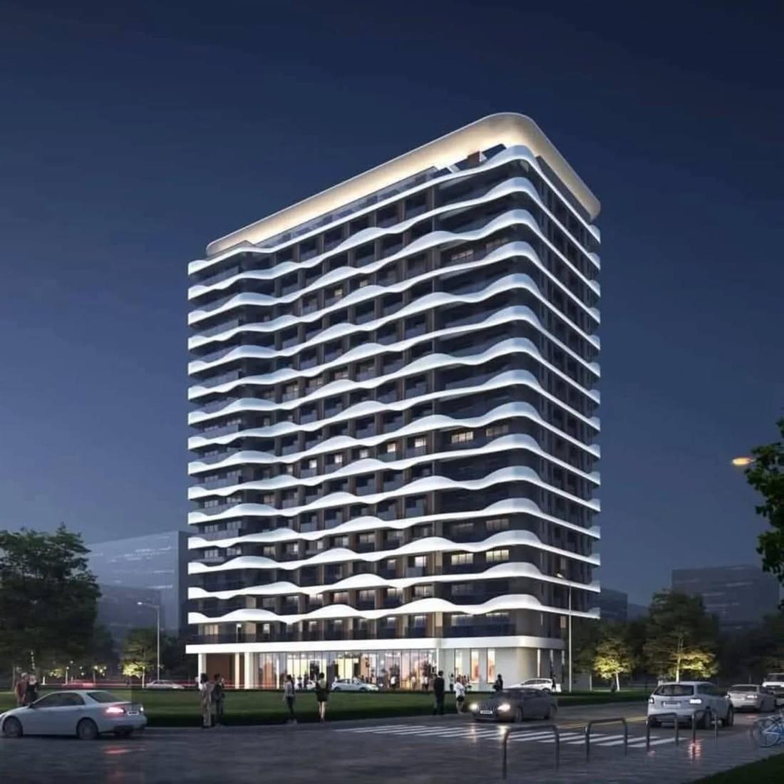Night render of Royal Mirema West, its balcony bands lit from below.